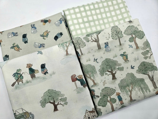 Four folded pieces of Wind in the Willows themed quilting cotton fabric in sage green, cream, and gingham check patterns.