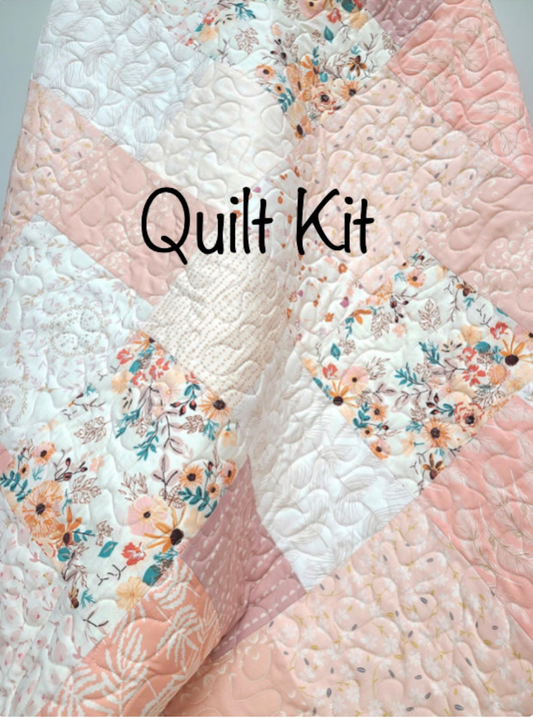 DIY pink farmhouse crib quilt kit showing a modern patchwork pattern with soft blush pink, cream, and light coral fabrics featuring delicate floral and geometric prints with an elegant swirled quilted texture